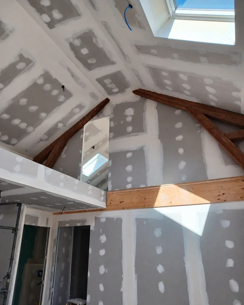 Pièce sous rampants avec mezzanine habillée en plaques de plâtre et fenêtre de toit, bandes et joints en cours